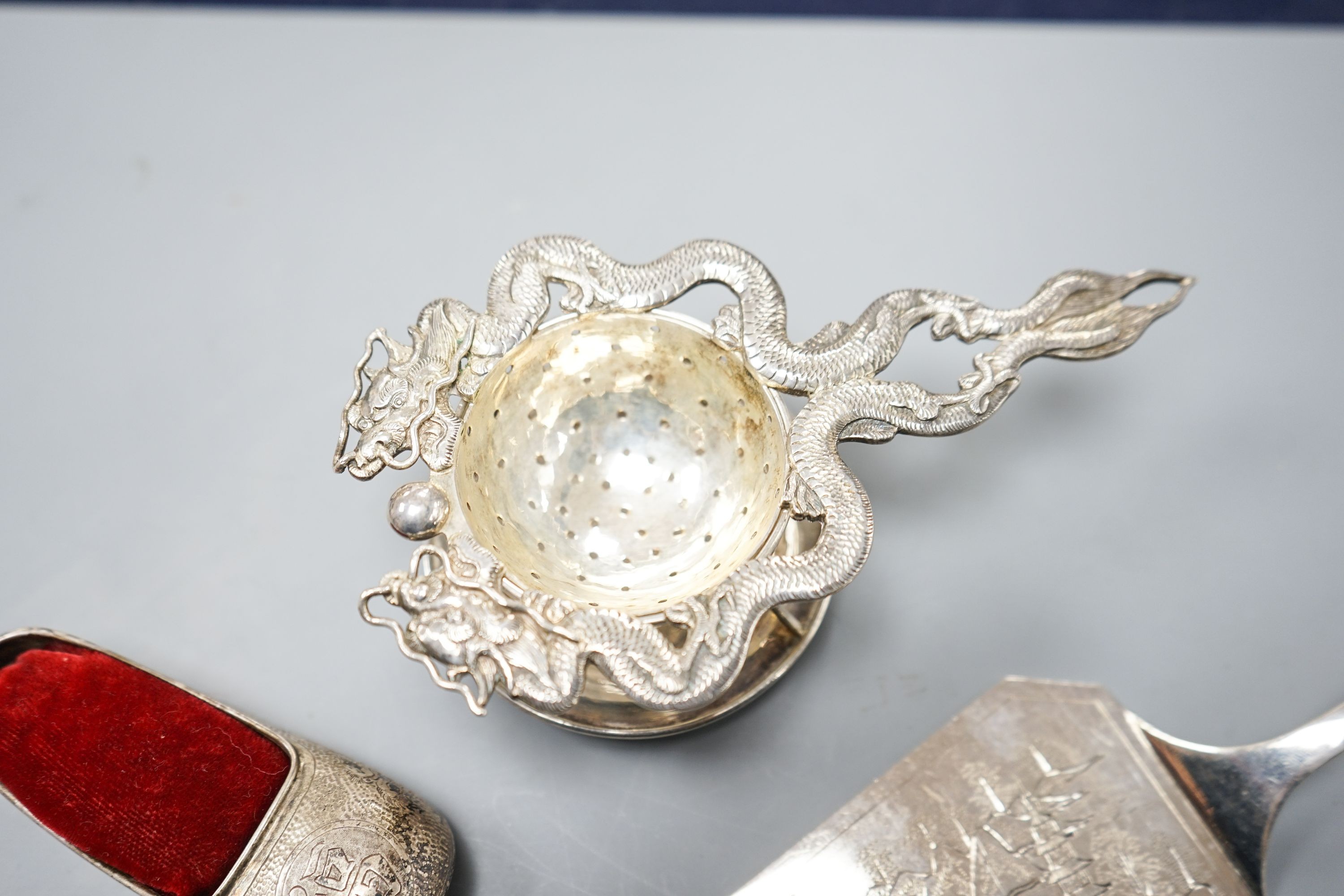 A Chinese white metal cake slice by Tack Hing, 24.4cm and a tea strainer on stand, pair of sugar tongs and pin cushion by Kingsburg, Hong Kong.